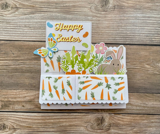 Easter-themed card with bunny, carrots, and flowers on a wooden surface