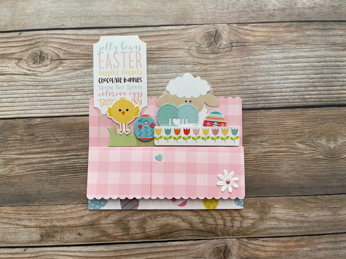 Easter-themed card with a lamb and chick design on a wooden surface