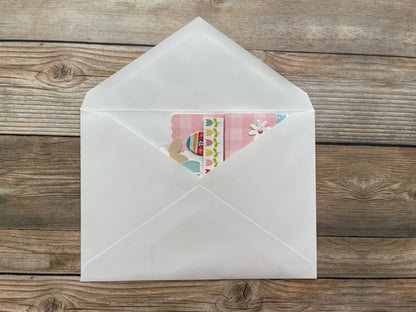 White envelope with a colorful card inside on a wooden surface