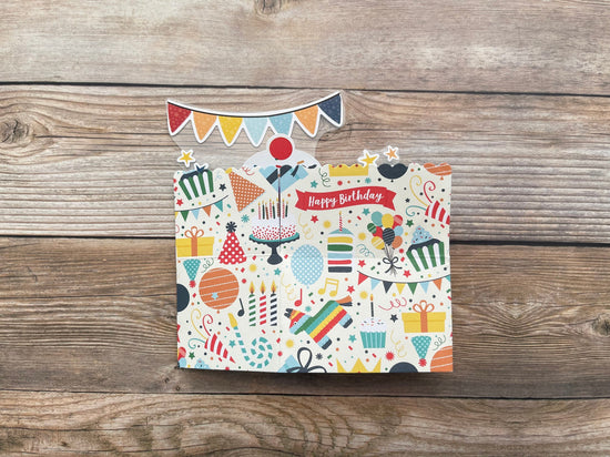 Colorful birthday-themed greeting card with decorative elements on a wooden surface