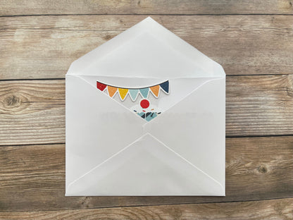 White envelope with colorful bunting design on a wooden surface