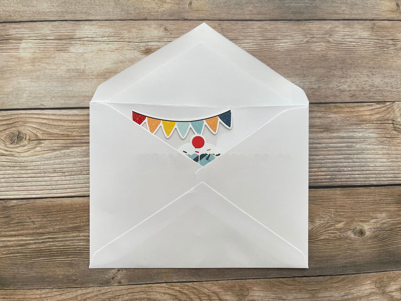 White envelope with colorful bunting design on a wooden surface