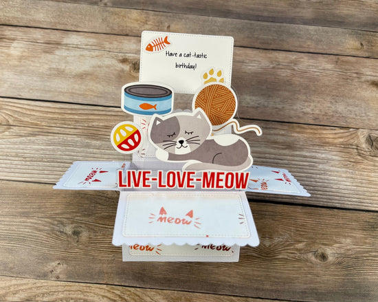 Pop-up card with cat-themed elements and 'Live Love Meow' text on a wooden surface