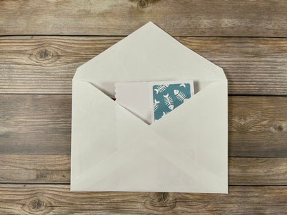 Beige envelope with a card featuring fish illustrations on a wooden surface
