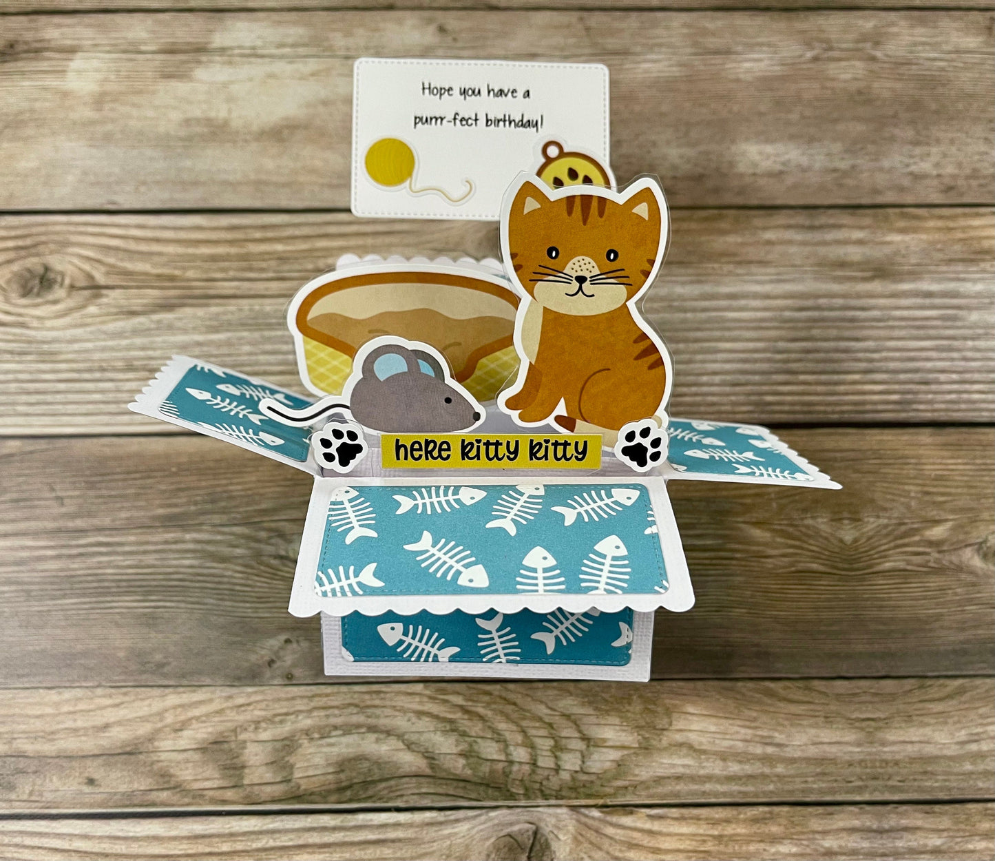 Cat-themed card with fish pattern on a wooden surface