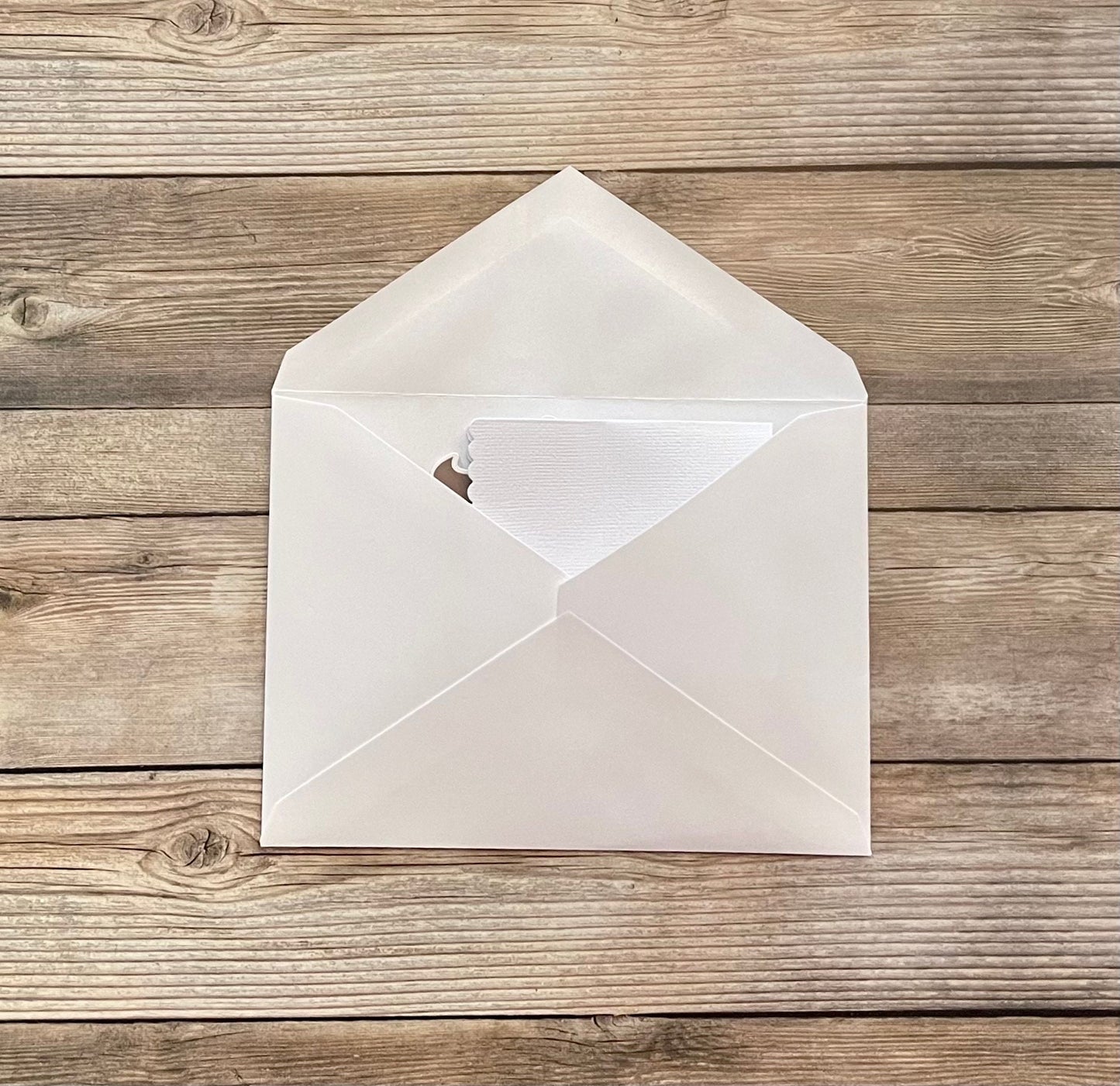 White envelope with a heart cutout on a wooden surface