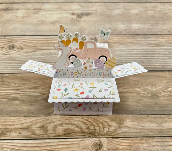 Easter-themed pop-up card with a truck and bunny on a wooden surface