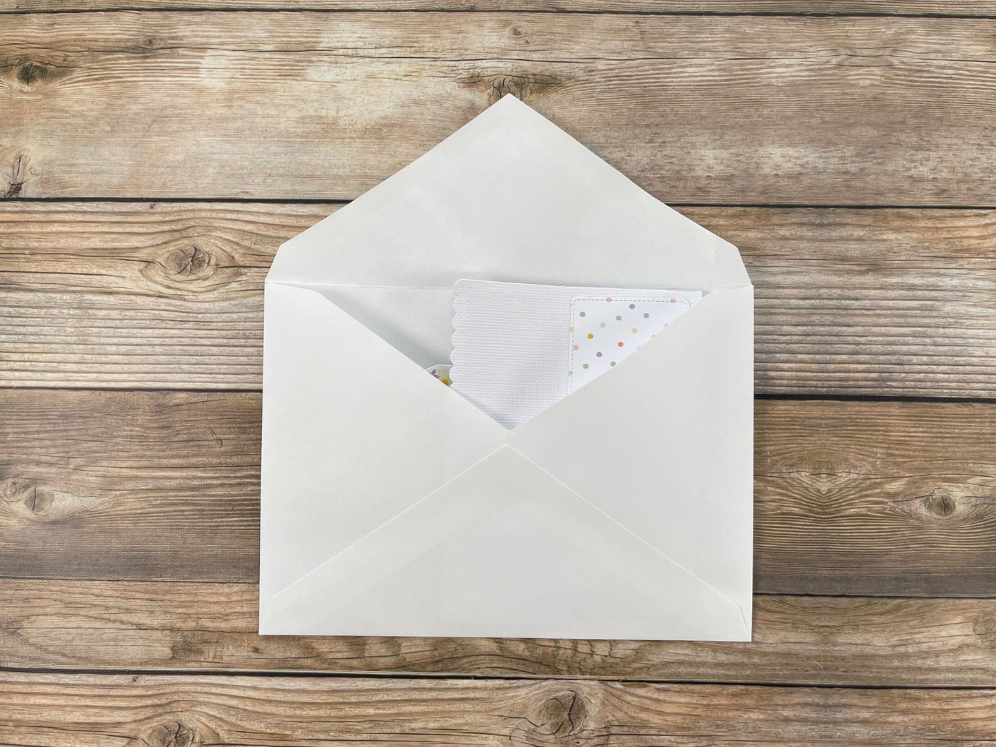White envelope with a small card inside on a wooden surface