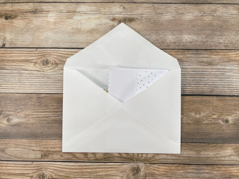 White envelope with a small card inside on a wooden surface