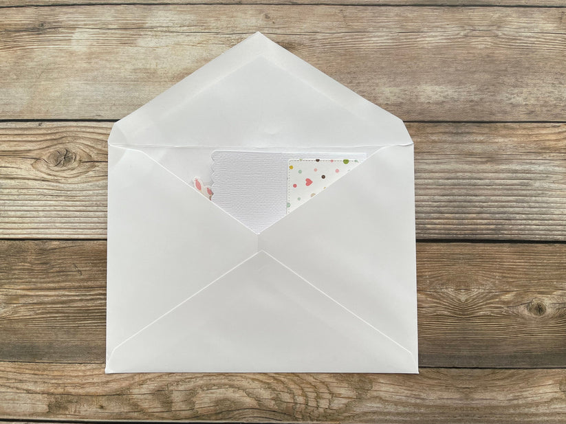 Open white envelope with a card inside on a wooden surface