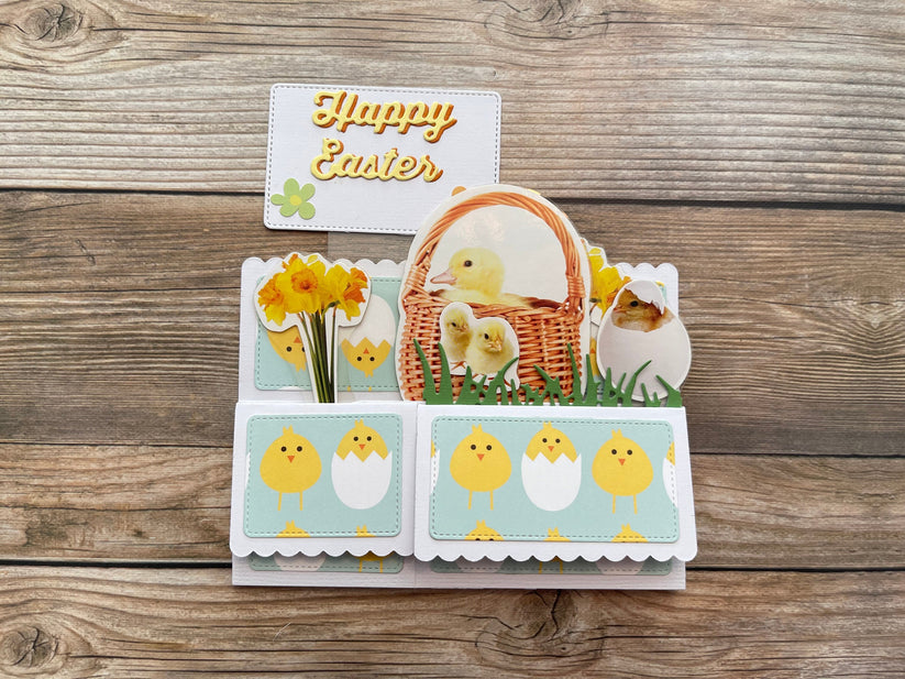 Easter-themed card with chicks, basket, and flowers on a wooden surface