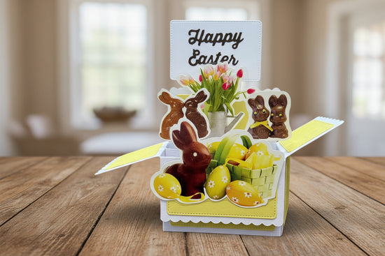 Pop-up Easter card with chocolate bunnies, eggs, and flowers on a wooden background