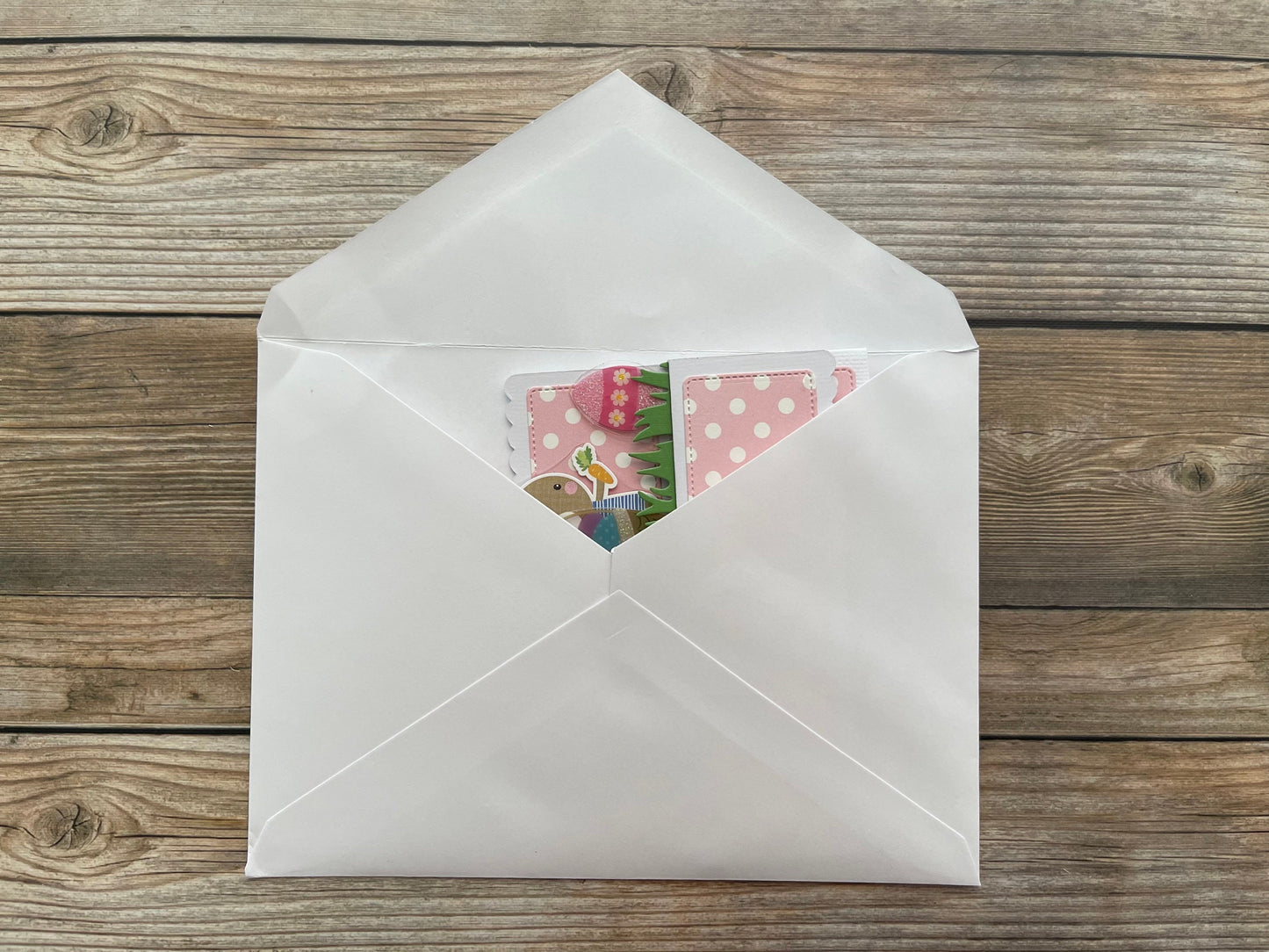 Open white envelope with colorful cards on a wooden surface