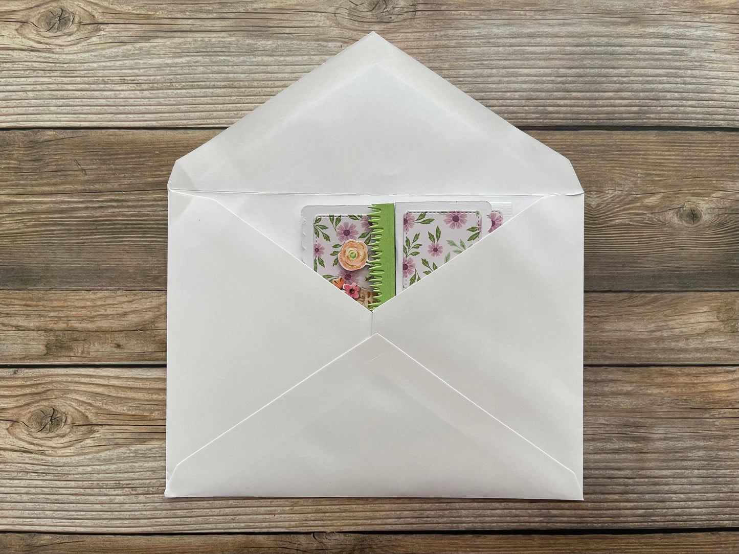 White envelope with a floral card on a wooden surface