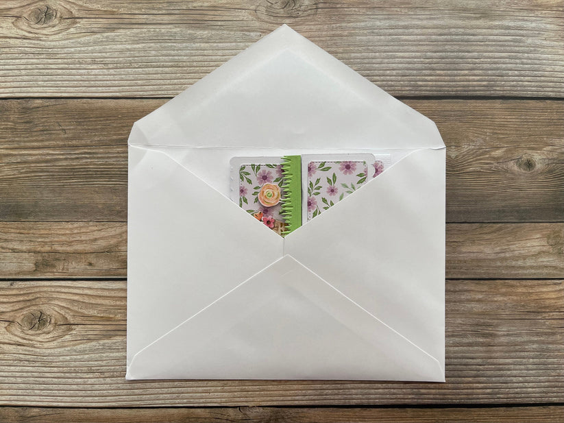 White envelope with a floral card on a wooden surface