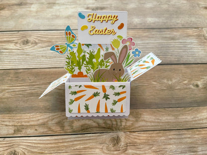 Easter-themed pop-up card with bunny, carrots, and flowers on a wooden background