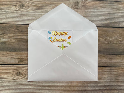 White envelope with a 'Happy Easter' card on a wooden surface