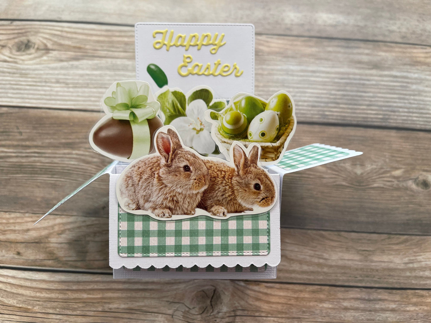Easter-themed card with bunnies, eggs, and 'Happy Easter' text on a wooden background