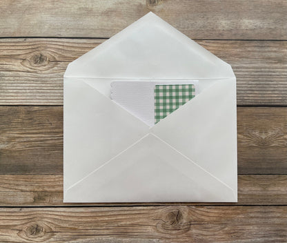 White envelope with a green checkered card on a wooden surface