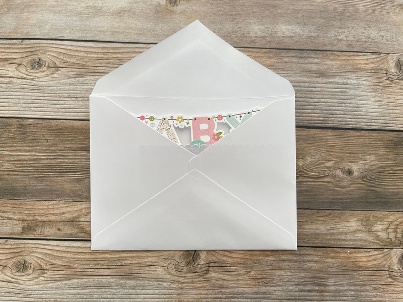 White envelope with a floral card inside on a wooden surface