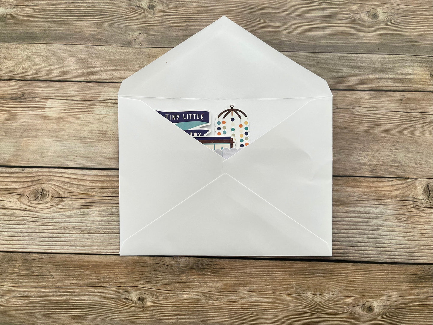 White envelope with a baby card inside on a wooden surface