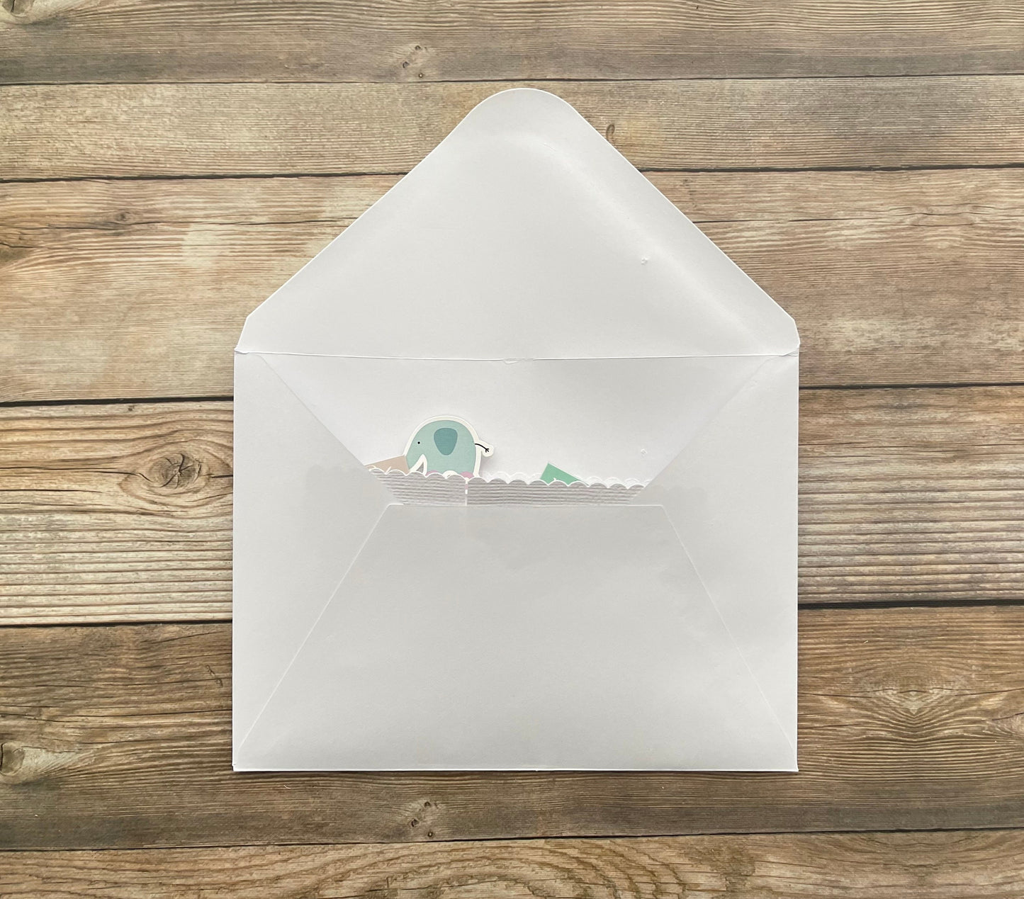 White envelope with a small green and white sticker on a wooden surface