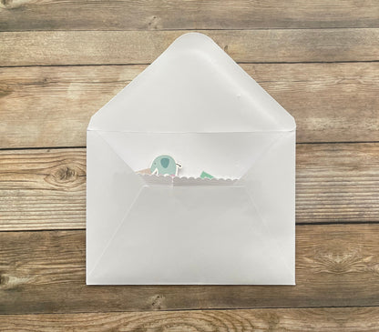 White envelope with a small green and white sticker on a wooden surface