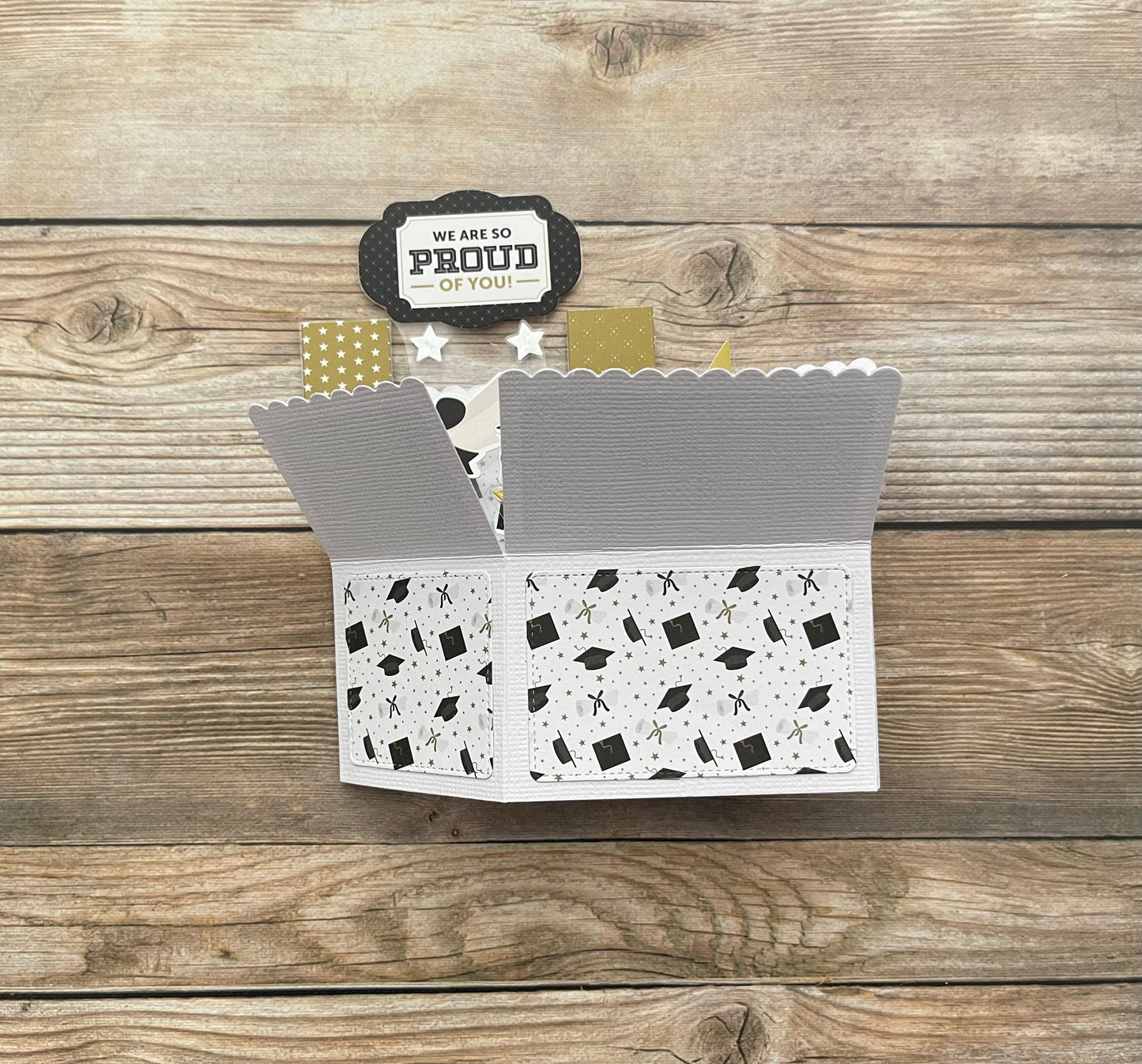 Open card with graduation-themed design on a wooden surface