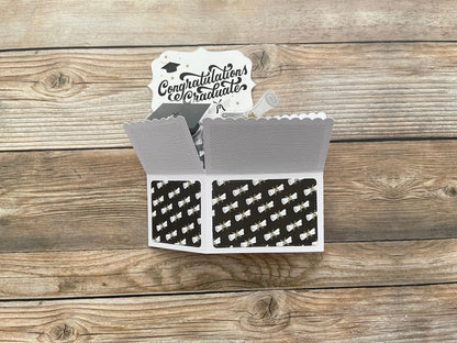 Graduation-themed card with 'Congratulations Graduate' message on a wooden surface