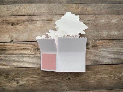 Small white box with a pink square on a wooden surface
