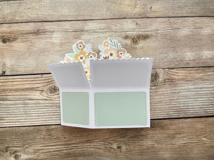 Open card with floral design on a wooden surface