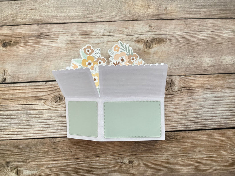 Open card with floral design on a wooden surface