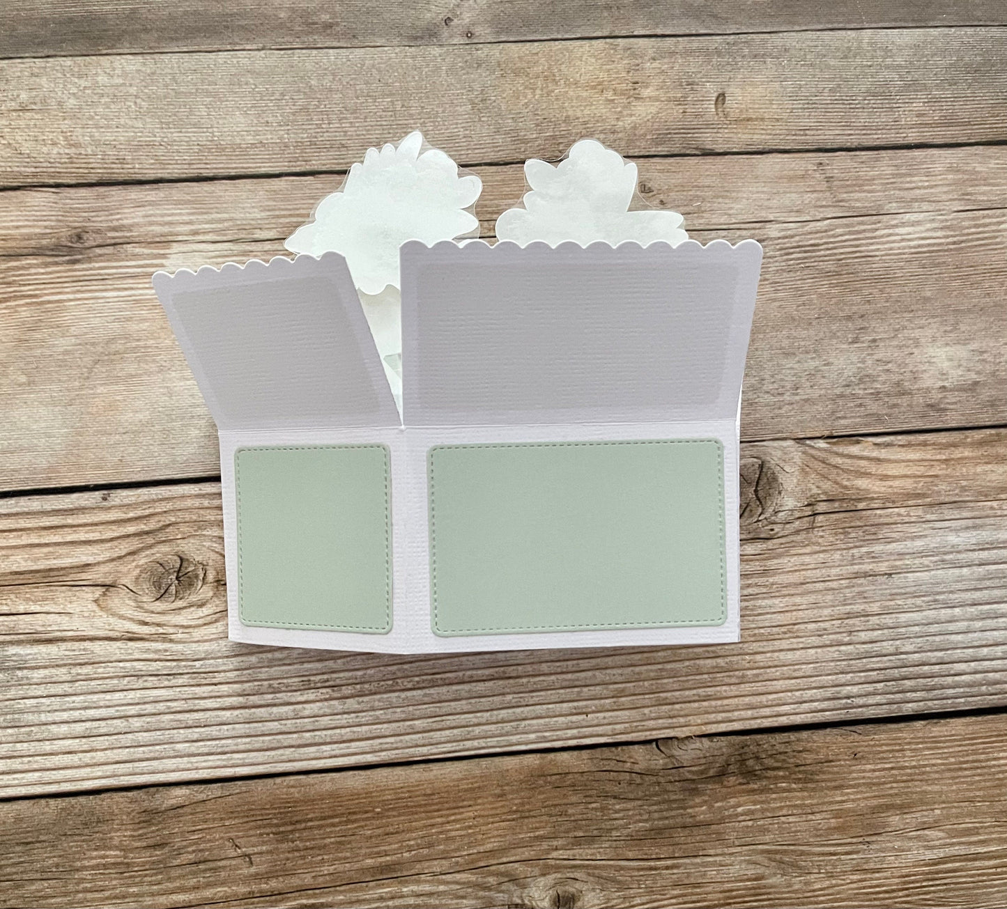 White scalloped card with green interior on a wooden surface