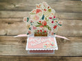 Pop-up birthday card with floral design on a wooden surface
