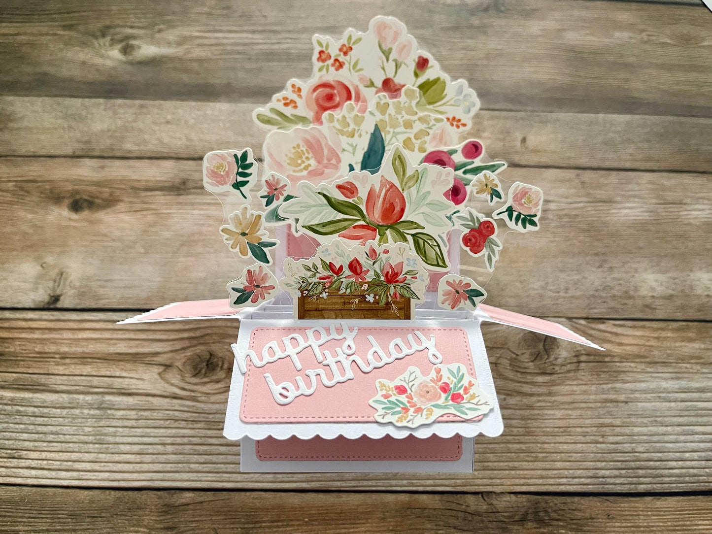Pop-up birthday card with floral design on a wooden surface