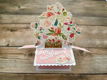 Pop-up birthday card with floral design on a wooden surface