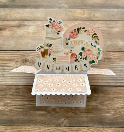 Decorative card with floral designs and 'MR & MRS' text on a wooden surface