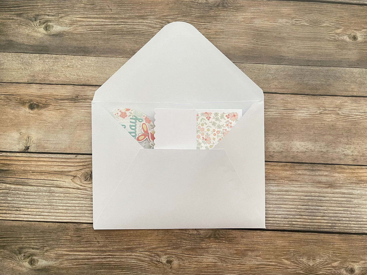 White envelope with floral stickers on a wooden surface