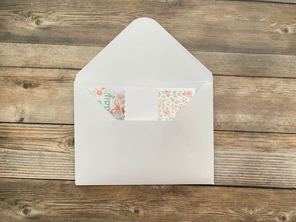 White envelope with floral stickers on a wooden surface