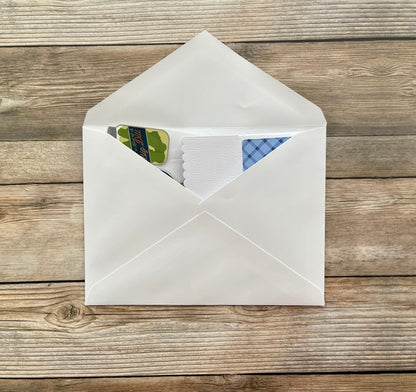 White envelope with stationery items on a wooden surface