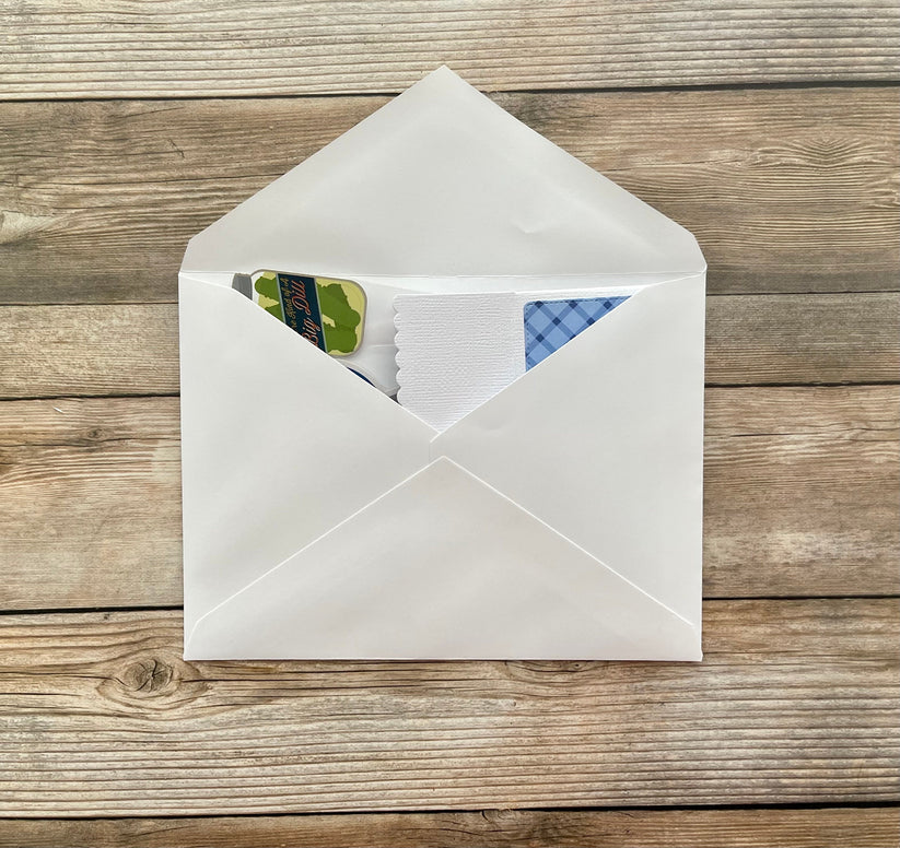 White envelope with stationery items on a wooden surface
