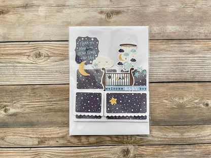 Baby shower card with crib and moon design on a wooden surface