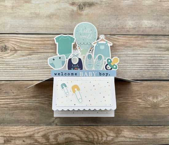 Baby shower card with illustrations of baby items on a wooden surface