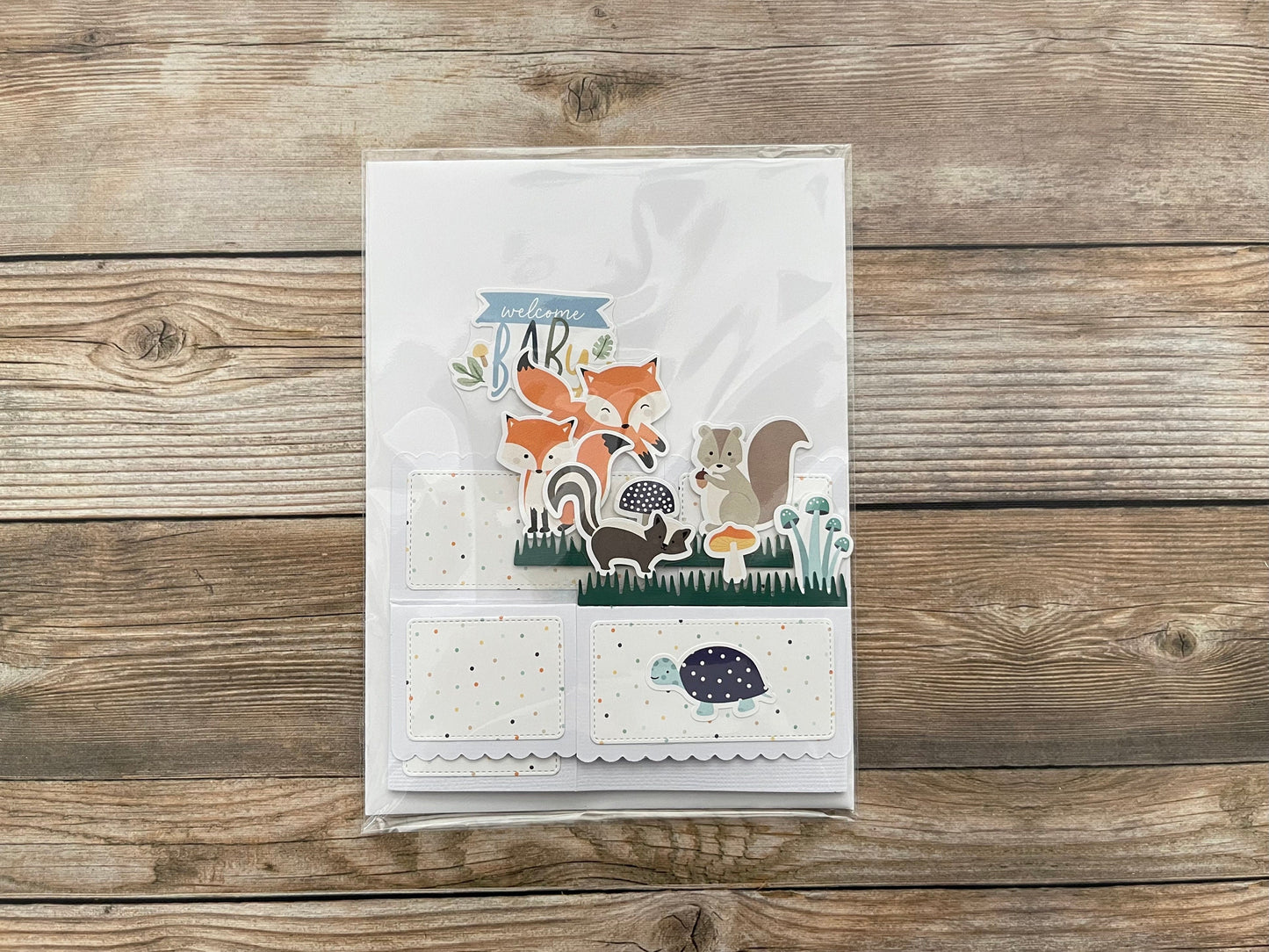Folded box po-up baby card with animal theme on a wooden surface