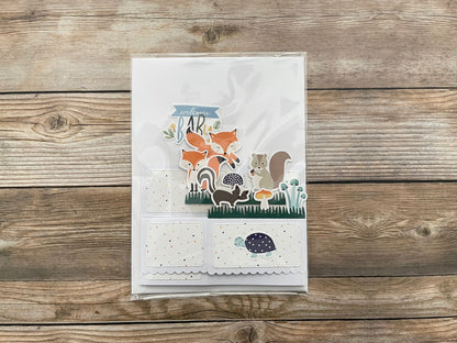 Folded box po-up baby card with animal theme on a wooden surface