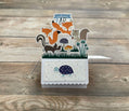 Welcome baby pop-up card with forest animal theme on a wooden surface
