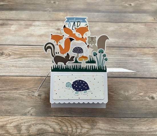 Welcome baby pop-up card with forest animal theme on a wooden surface
