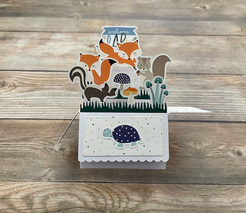 Welcome baby pop-up card with forest animal theme on a wooden surface