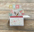 Baby-themed card with decorative elements on a wooden surface