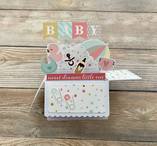 Baby-themed card with decorative elements on a wooden surface